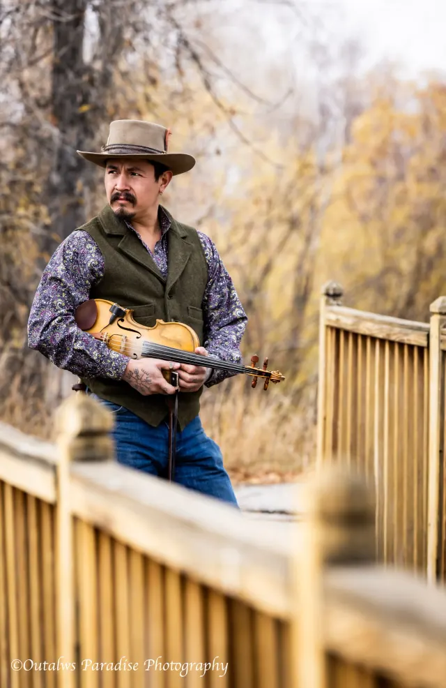 Rooster holding his fiddle on a wooden bridge.