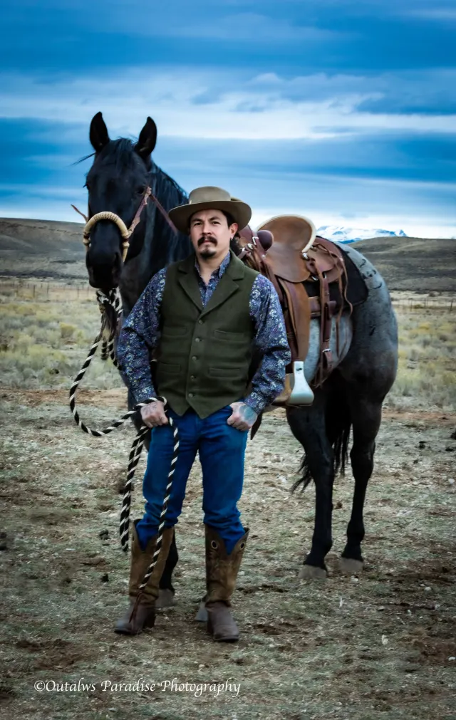Rooster standing beside a dark horse in an open field.